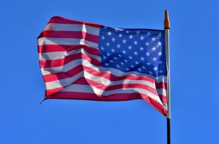 Grafika przedstawia flagę USA, powiewającą na wietrze.