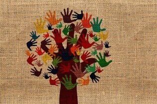 Grafika przedstawia drzewo z liśćmi w postaci odbitych kolorowych ludzkich dłoni.